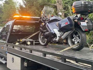 A tow truck hauling a motorcycle on a flatbed. 